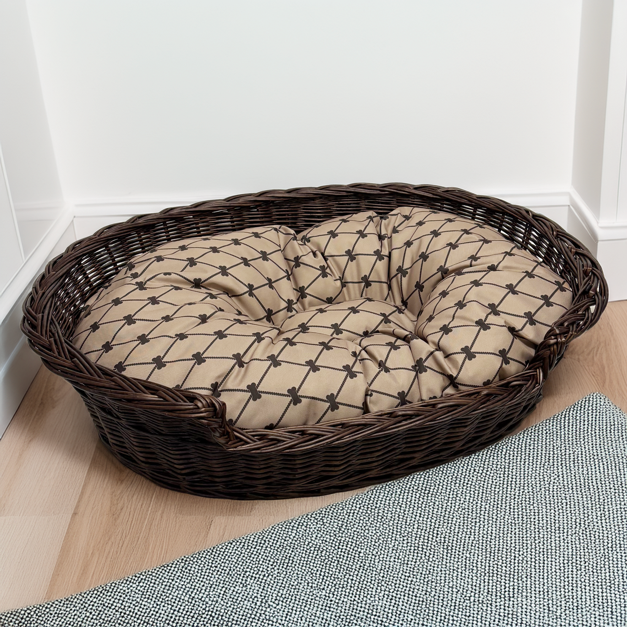 Wicker pet bed with a cushion on a wooden floor.